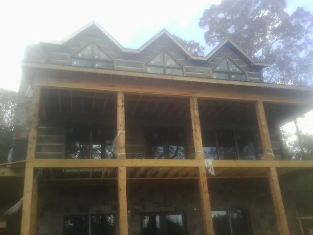 Dormers and porch framing on a large log home under construction — Roof Coating work by our crew in Hiawatha