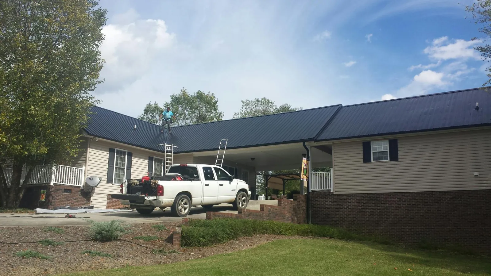 Black metal roof over a home and attached breezeway with ladders set in Hiawatha
